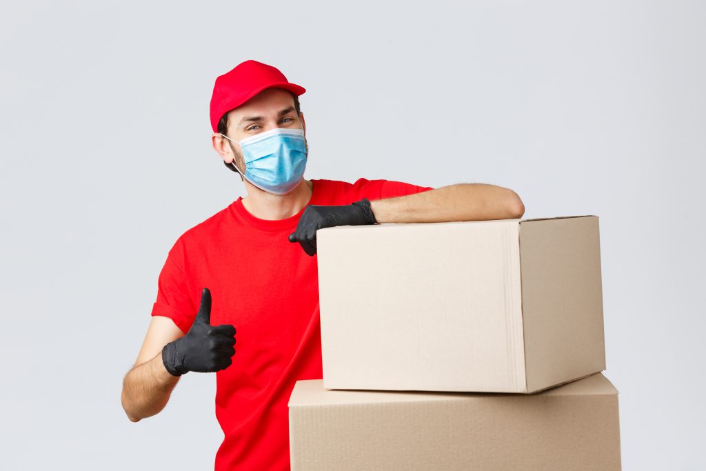 packages parcels delivery covid 19 quarantine transfer orders confident courier red uniform gloves medical mask encourage call service show thumb up lean boxes